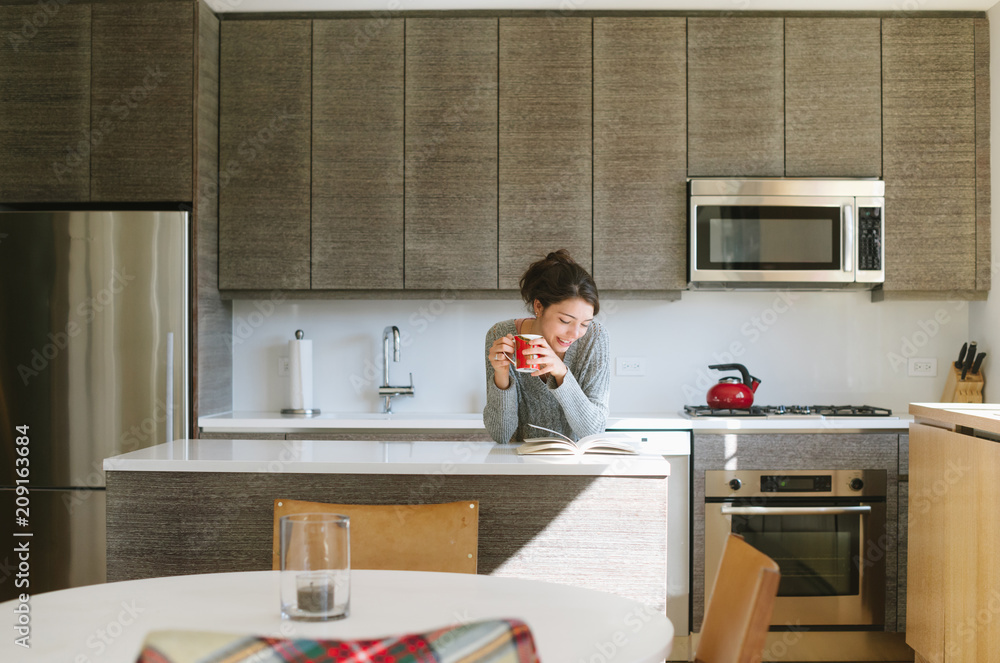 Young woman reading in kitchen at home Young woman reading in kitchen at home