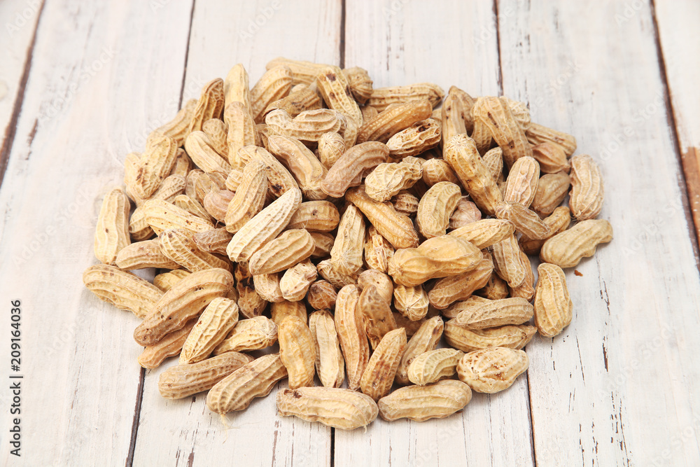 Pile of peanuts with nutshell on wood background Pile of peanuts with nutshell on wood background