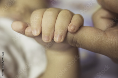 The hands of the mother hold the baby's hand with love and caring.