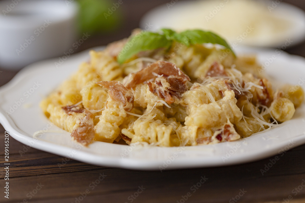 Homemade Pasta carbonara Italian with Bacon, eggs, Parmesan Cheese on white plate on a dark background.