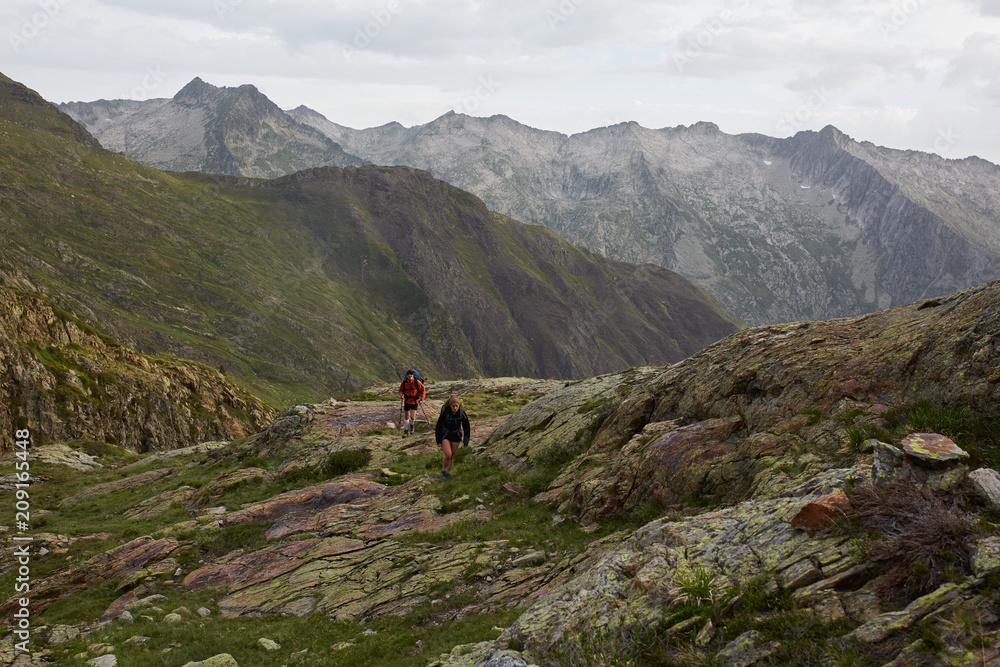 Scenic landscape with a couple of hikers walking the green and rocky mountains Scenic landscape with a couple of hikers walking the green and rocky mountains