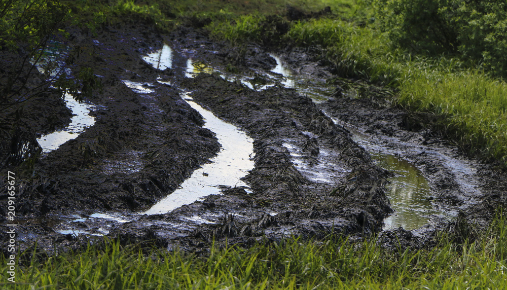 Dirty country road wet dirt, impassability. Mud and puddles on dirt road. Traces from tractors and cars.. Dirty country road wet dirt, impassability. Mud and puddles on dirt road. Traces from tractors and cars..
