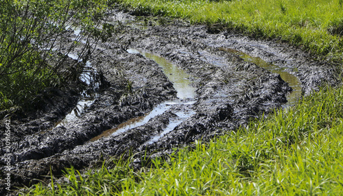 Dirty country road wet dirt, impassability. Mud and puddles on dirt road. Traces from tractors and cars..