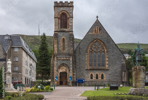 Bild auf Leinwand Fort William, Scotland - June 11, 2012: Frontal view on Duncansburgh Church of Scotland, Macintosh Parish, located on The Parade in downtown under gray sky with hills in back