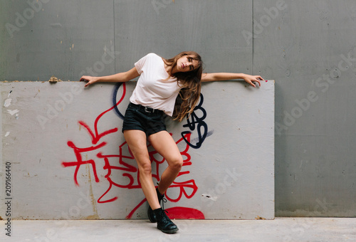 An attractive young woman wearing shorts and T-shirt amongst concrete structures in a city photo