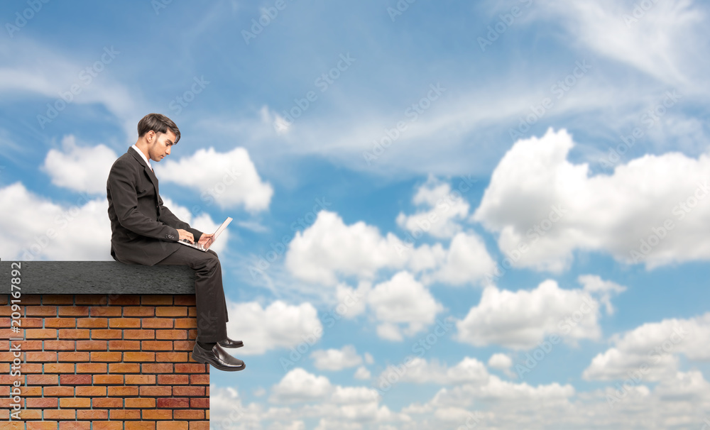 Concept idea.young businessman sitting on building top with computer in hands and red graph background.Asian businessmen sitting on the building are analyzing future jobs, riches, advances, stock Concept idea.young businessman sitting on building top with computer in hands and red graph background.Asian businessmen sitting on the building are analyzing future jobs, riches, advances, stock