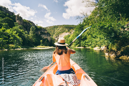 paddler in a canoe on a river in a lush green valley photo