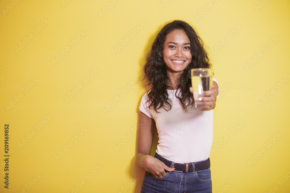 asian girl smiling while offering a glass of mineral water asian girl smiling while offering a glass of mineral water