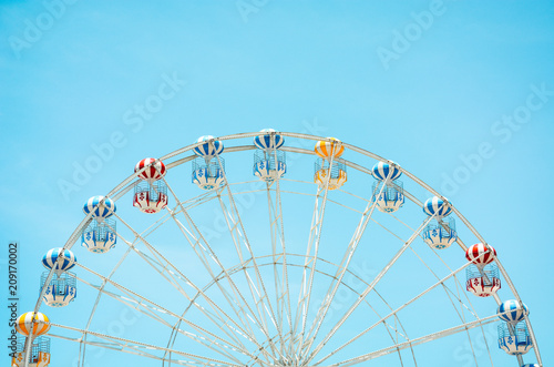 front view of half retro colorful ferris wheel at amusement park over blue sky background  copy space  vintage effect