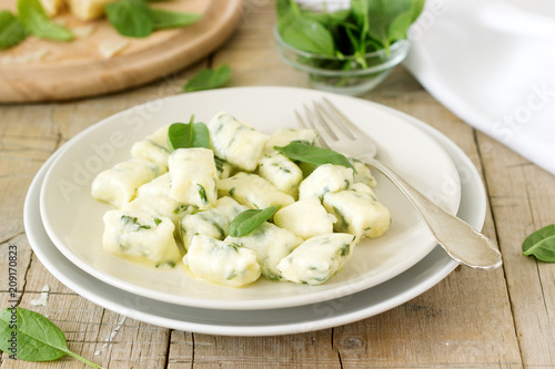 Homemade gnocchi with ricotta, cheese and spinach on a light plate.