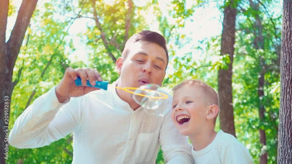 Father with his son blowing soap bubbles, fun family pastime, a child having fun with his dad Father with his son blowing soap bubbles, fun family pastime, a child having fun with his dad