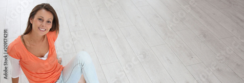 Young woman sitting on brand new home floor, template