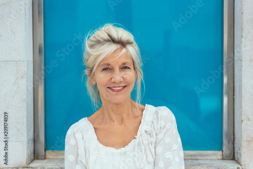 Smiling blond senior woman in white top