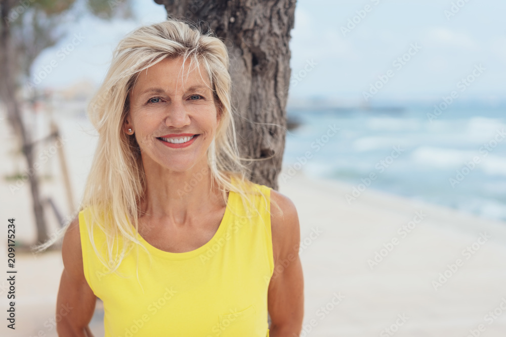 Attractive tanned blond woman standing on a beach Attractive tanned blond woman standing on a beach