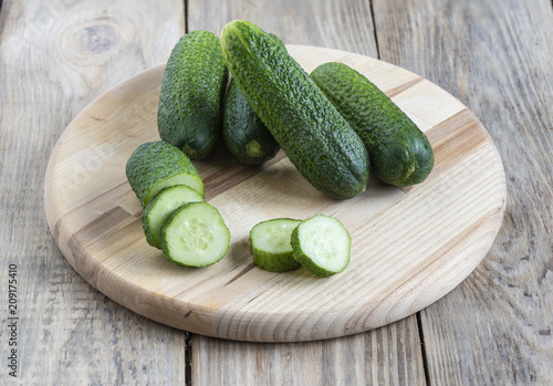 Several whole fresh cucumber and slices of cucumber on a cutting photo