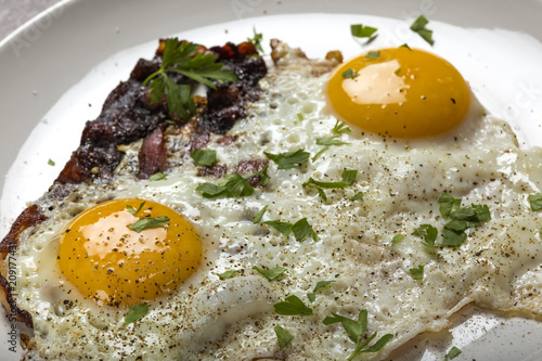 Bacon and eggs with ground pepper and parsley leaves