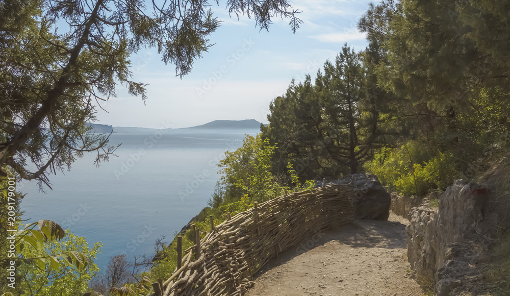 Fototapeta premium A mountain path, fenced with a wicker fence, running along the coast.Crimea.