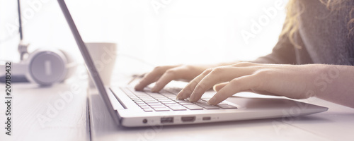 Woman sitting at desk and connecting with her laptop, she is working and typing on the keyboard, hands close up