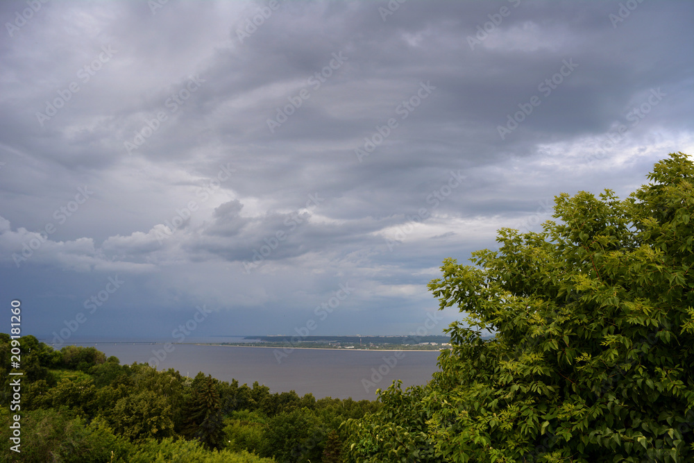 Before the storm. Thunderstorm sky over forest and river in cloudy summer day.