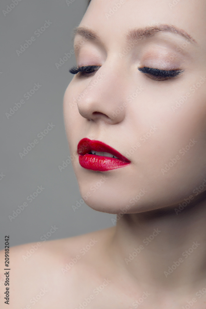 Stylish girl portrait with red lips and clean skin on grey isolated background. Stylish girl portrait with red lips and clean skin on grey isolated background.