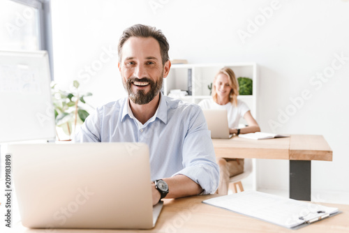 Laughing man manager working on laptop