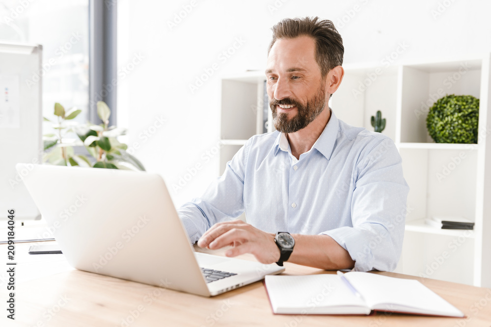Smiling businessman working on laptop computer Smiling businessman working on laptop computer