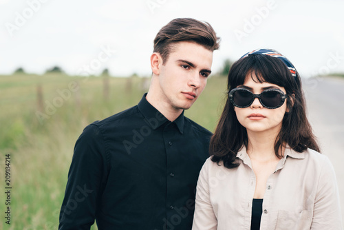 Cute young guy standing next to a beautiful girl on a green background behind a city