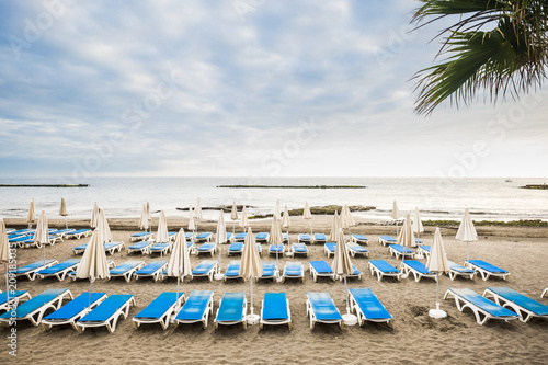 Fototapeta Naklejka Na Ścianę i Meble -  nobody at the beach un empty clients summer business. many seats and closed umbrellas in tropical summer place. vacation and relax concept with seats background and quiet ocean