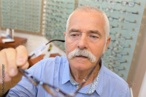 senior man trying new eyeglasses on optical store