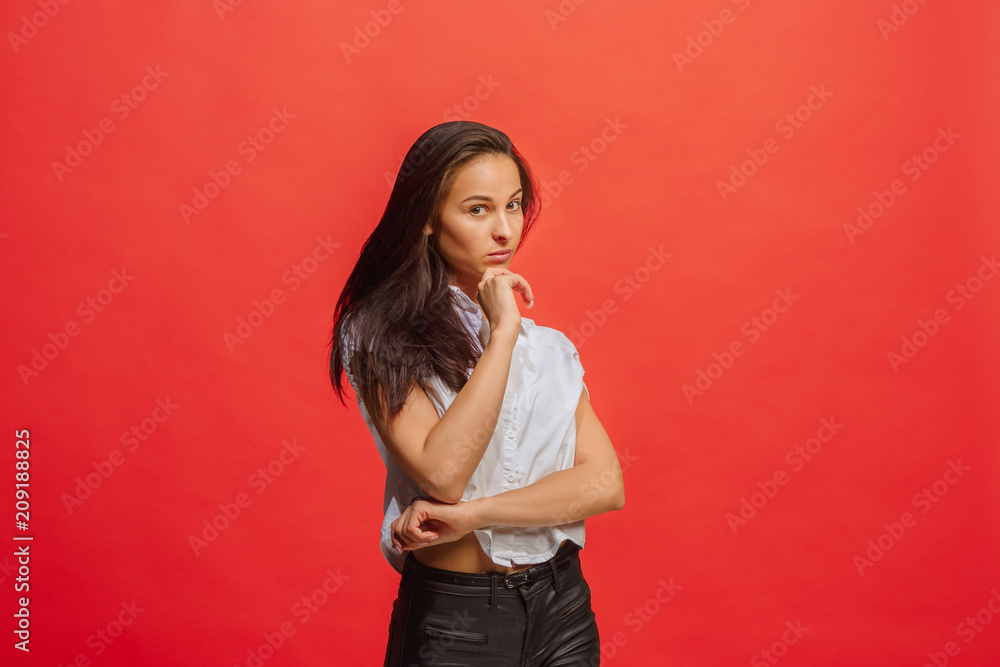 The serious business woman standing and looking at camera against red background. The serious business woman standing and looking at camera against red background.