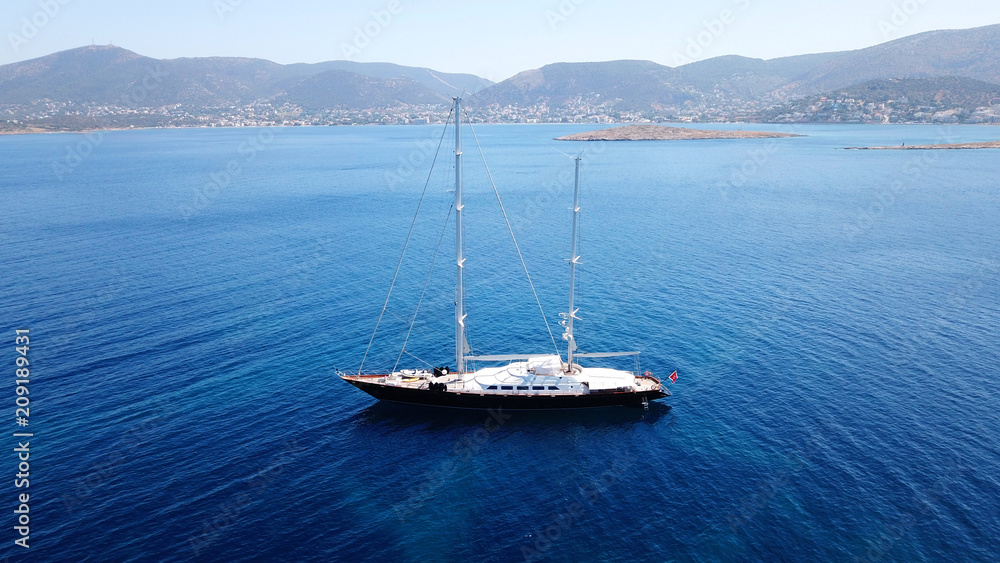 Fototapeta premium Aerial drone bird's eye view photo of wooden deck luxury sail boat docked in mediterreanean deep blue waters