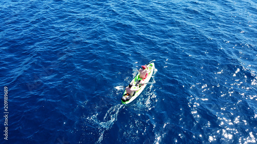 Aerial drone bird's eye view of sport kayak operated by 2 young men in deep blue open sea waters © aerial-drone