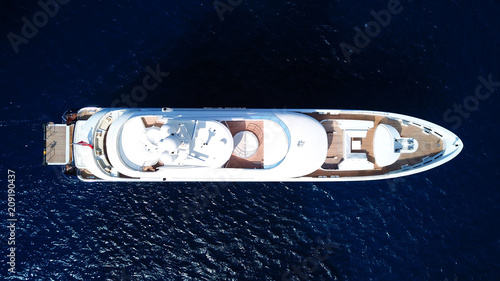 Fototapeta Naklejka Na Ścianę i Meble -  Aerial drone bird's eye top view photo of luxury yacht with wooden deck docked in deep blue waters of Mykonos island, Cyclades, Greece