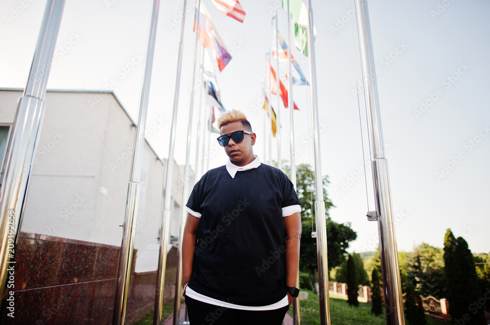 Stylish arabian muslim boy with originally hair posed on streets, against flags of different countries. Stylish arabian muslim boy with originally hair posed on streets, against flags of different countries.