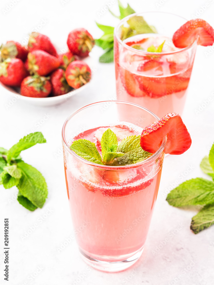 Glasses of a fresh pink lemonade. Strawberry soda with mint on a white wooden table. Glasses of a fresh pink lemonade. Strawberry soda with mint on a white wooden table.