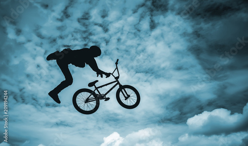 Silhouette of a man doing an jump with a bmx bike.