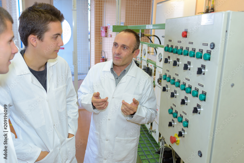 Obraz premium Man explaining control panel to male students