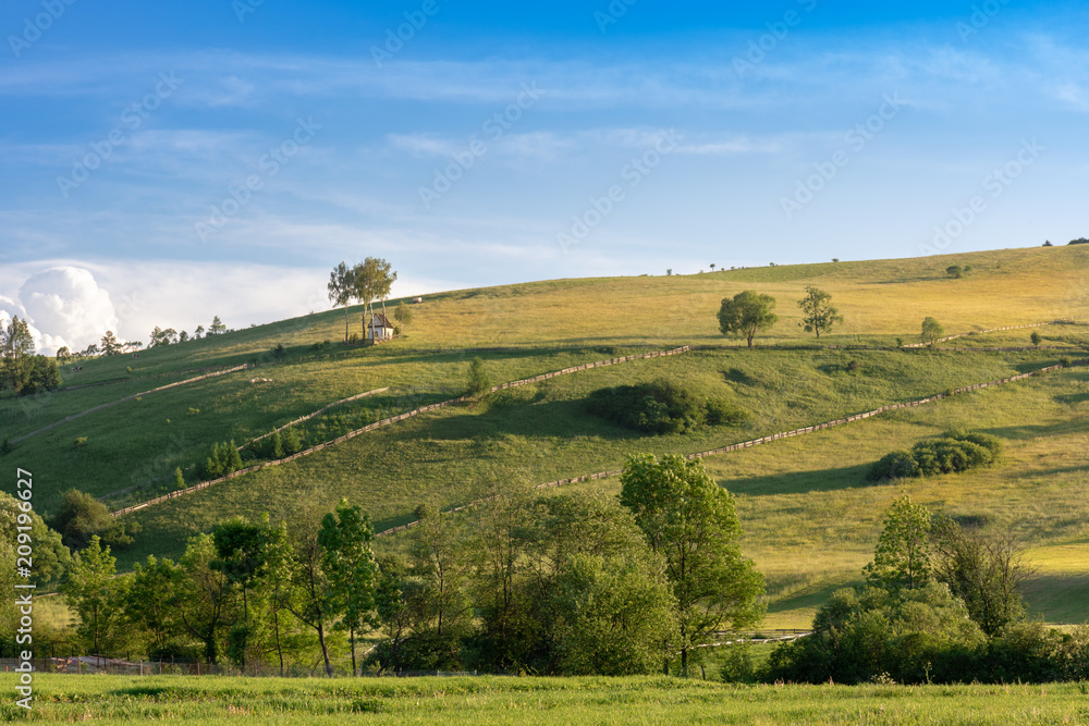 Fototapeta premium Tiny, picturesque chapel on a hill, among meadows and arable fields, a Polish village in the Pieniny