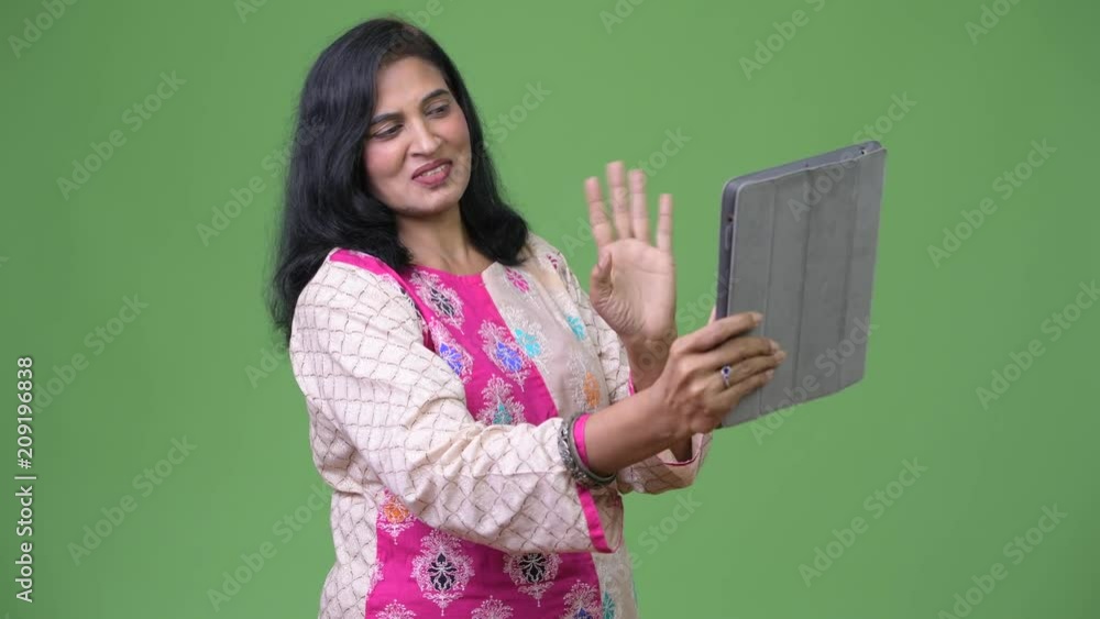 Mature happy beautiful Indian woman video calling with digital tablet Mature happy beautiful Indian woman video calling with digital tablet