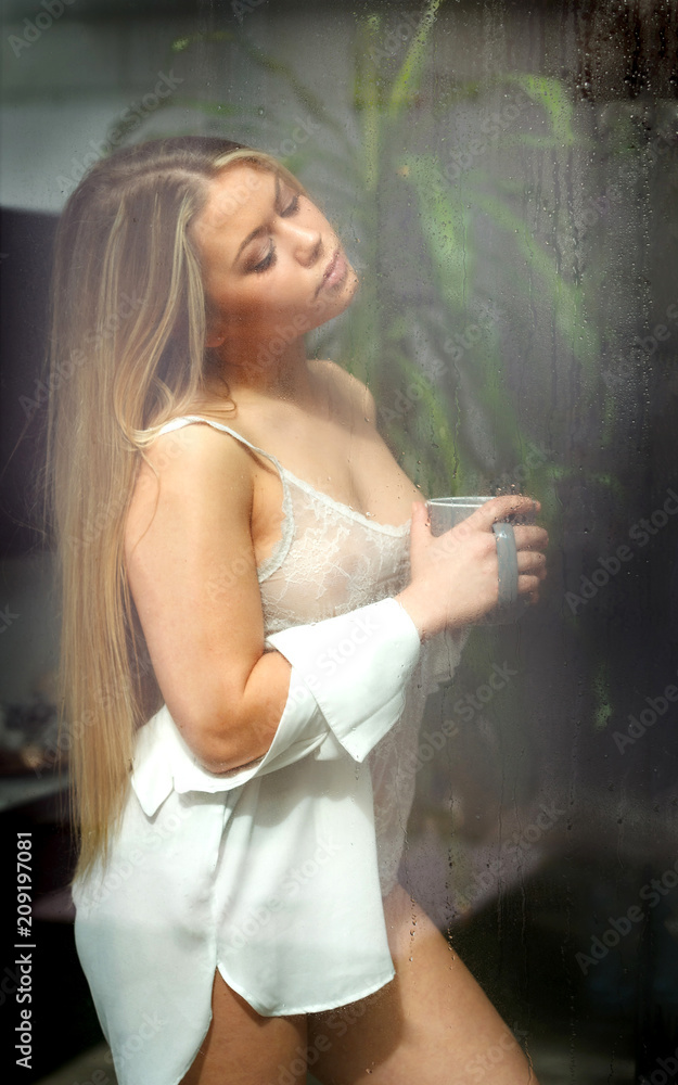 Obraz premium Sensual girl in nighdress drinking coffee at home in a raining day