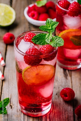 Raspberry Mojito Lemonade with lime and fresh mint in glass on wooden background