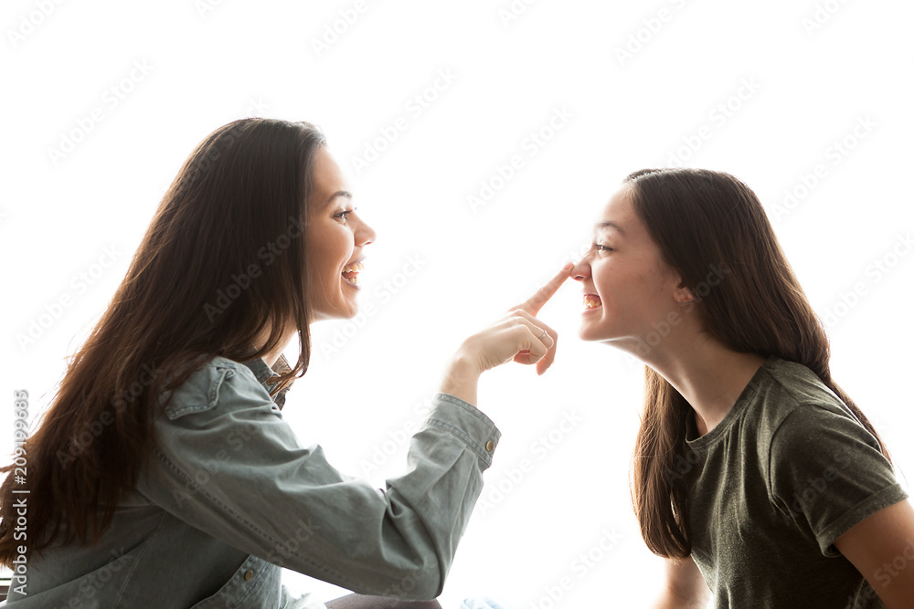 Two sisters playing with each other and having a great time together over white background Two sisters playing with each other and having a great time together over white background