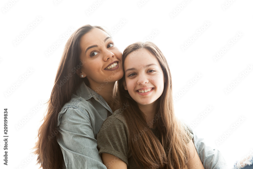 Portrait of two sisters next to a big bright window. Happy family Portrait of two sisters next to a big bright window. Happy family