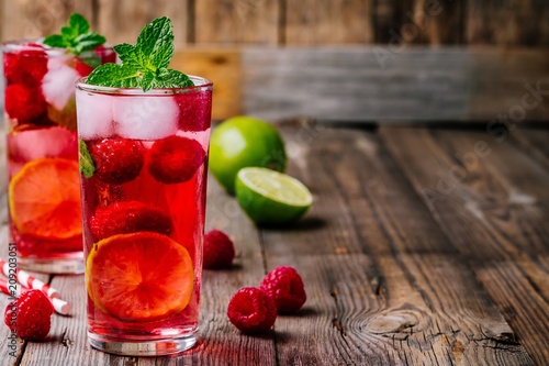 Tableau sur toile Raspberry Mojito Lemonade with lime and fresh mint in glass on wooden background