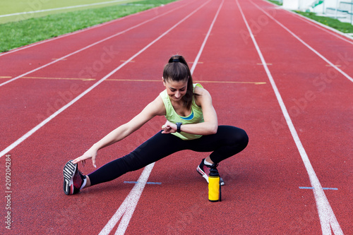 Sporty woman looking at smartwatch while doing exercise