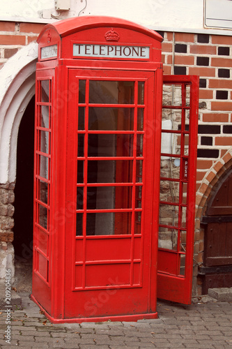 classic red English phone booth on the street, open door, no people