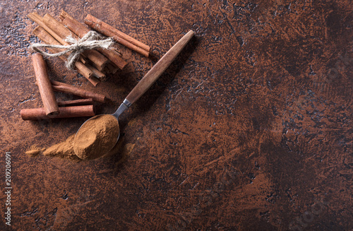 Fototapeta Naklejka Na Ścianę i Meble -  Cinnamon sticks and powder in spoon on a old copper table .