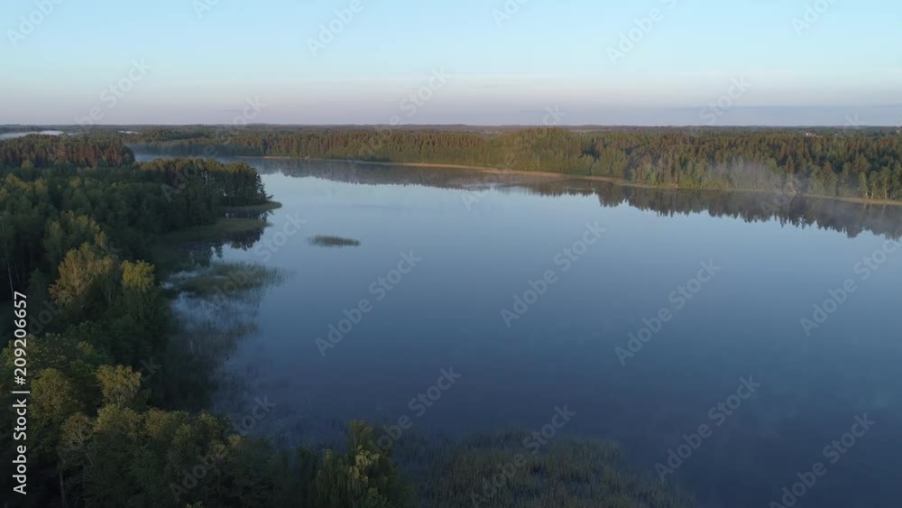 Aerial shot of a lake in a forest during sunrise in Latgale, Latvia Aerial shot of a lake in a forest during sunrise in Latgale, Latvia