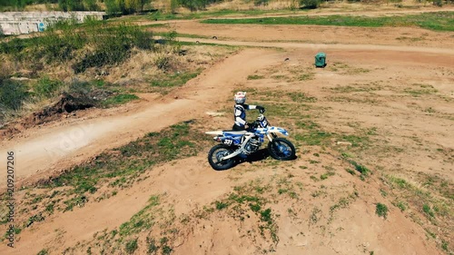 Equipped rider is standing with his motorbike in the middle of an outdoor track photo