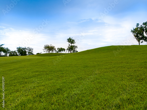 slope hill lay out in green golf course with trees and blue sky